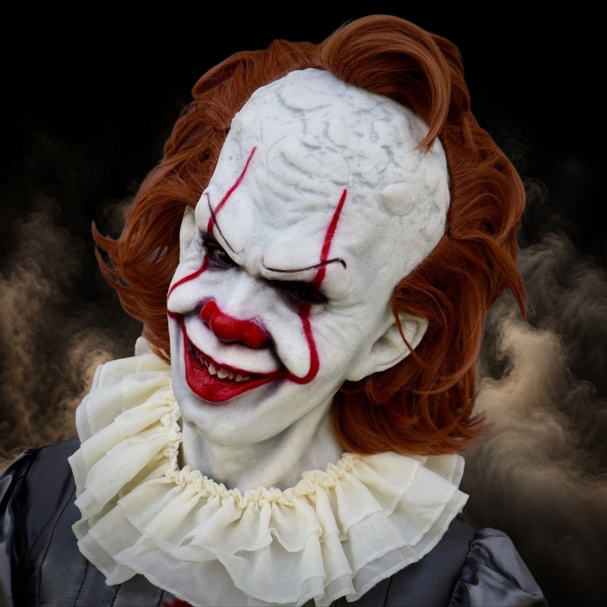 Clown mask with long orange hair and red lines painted across the eyes